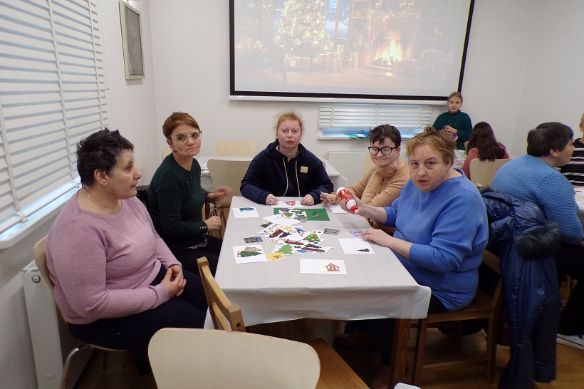 Praca mieszkańców i opiekunów podczas warsztatów tworzenia kartek świątecznych.